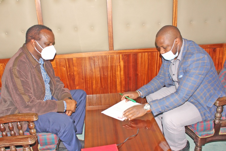 Christian Aid Country Manager Njoroge Mucheru (Right)  Prof. James Machoki (Left) Dean Faculty of Health Sciences sign vehicle transfer documents.